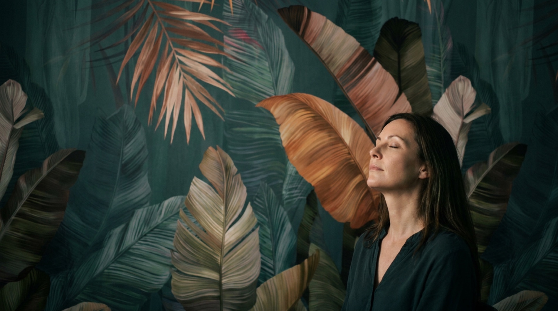 A serene woman against the botanical mural inside Kolibri Aesthetics